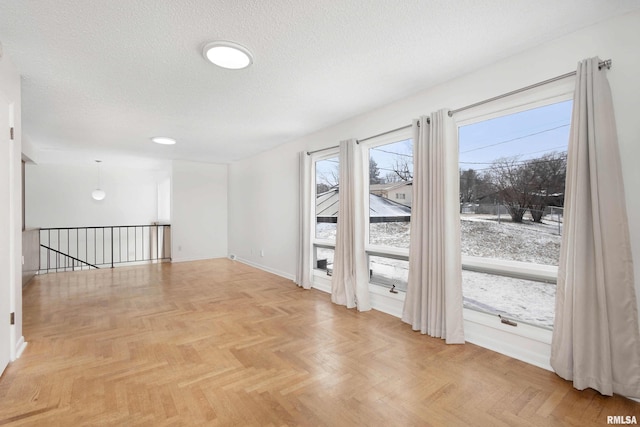 spare room with light parquet flooring and a textured ceiling