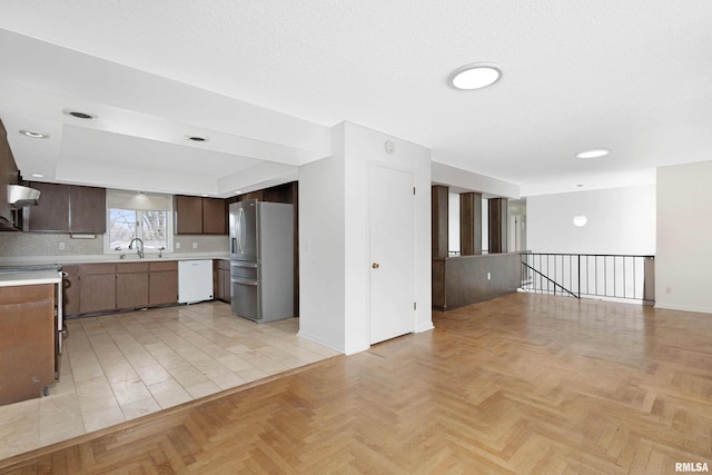 kitchen with dishwasher, sink, dark brown cabinetry, stainless steel fridge with ice dispenser, and light parquet flooring