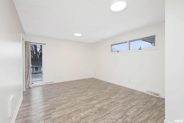 spare room with a textured ceiling and light wood-type flooring