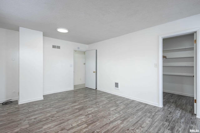 unfurnished bedroom with wood-type flooring, a walk in closet, and a closet