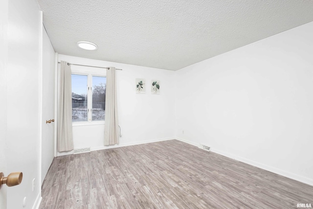 empty room with wood-type flooring and a textured ceiling