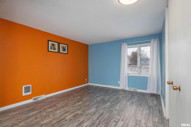 spare room featuring hardwood / wood-style floors and a textured ceiling