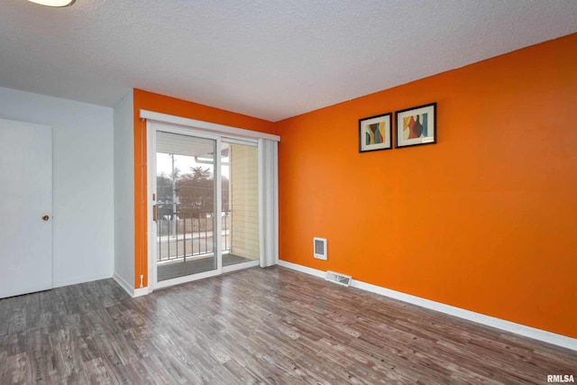 unfurnished room with hardwood / wood-style floors and a textured ceiling