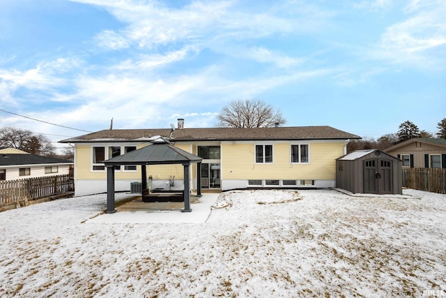 snow covered property featuring a gazebo, a storage unit, and central AC