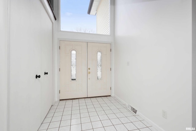 entrance foyer featuring a towering ceiling and light tile patterned floors