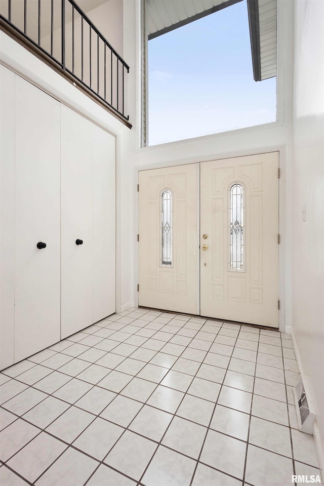 foyer with light tile patterned floors, a towering ceiling, and plenty of natural light