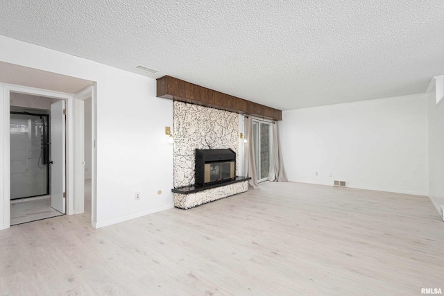 unfurnished living room featuring a textured ceiling, a fireplace, and light hardwood / wood-style flooring