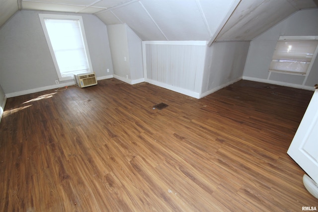 additional living space featuring hardwood / wood-style flooring, lofted ceiling, and an AC wall unit