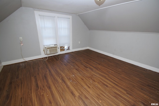 additional living space with cooling unit, dark wood-type flooring, and vaulted ceiling