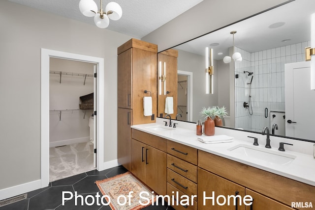 bathroom with tile patterned flooring, vanity, a textured ceiling, and walk in shower