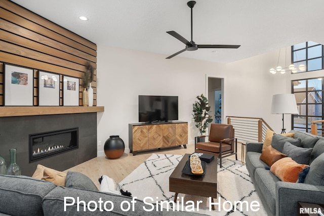 living room featuring ceiling fan, a large fireplace, and wood-type flooring