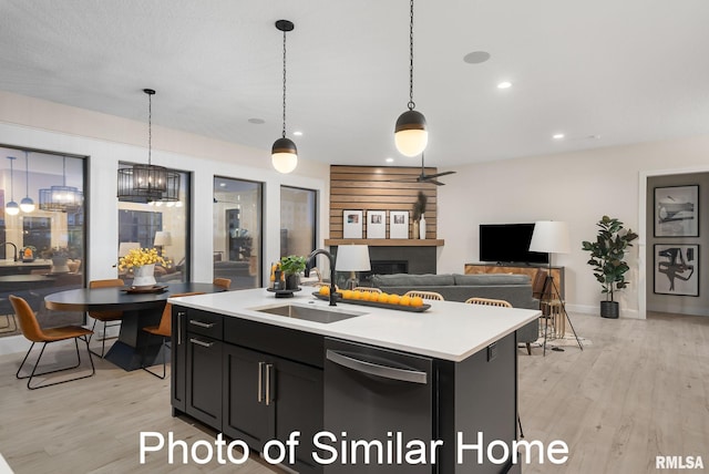 kitchen featuring an island with sink, decorative light fixtures, black dishwasher, and sink