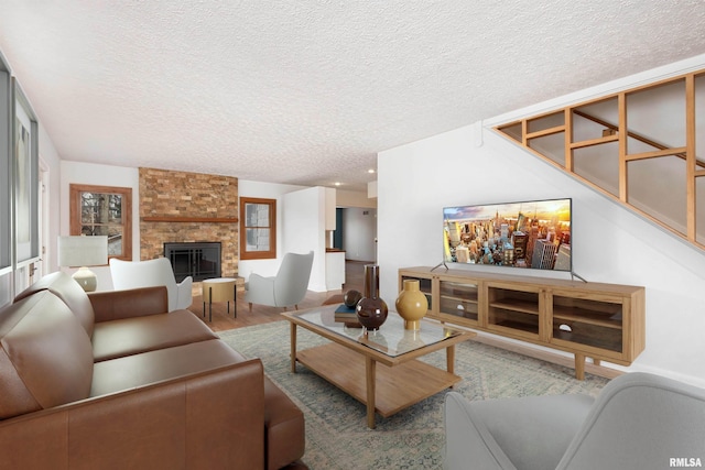 living room featuring hardwood / wood-style floors, a large fireplace, and a textured ceiling