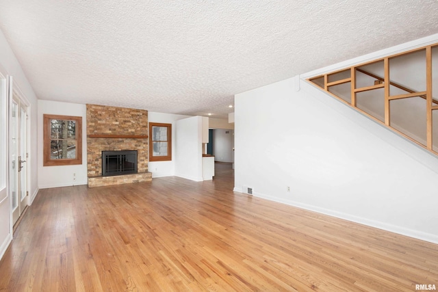 unfurnished living room with light hardwood / wood-style floors, a large fireplace, and a textured ceiling