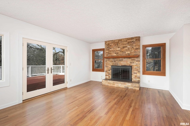 unfurnished living room with wood-type flooring, a brick fireplace, and a textured ceiling