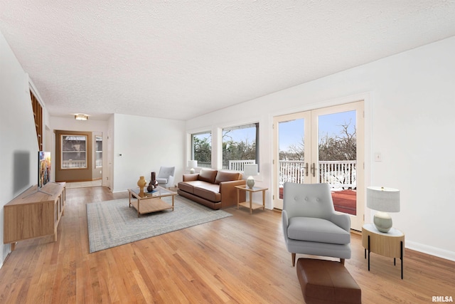 living room featuring french doors, a textured ceiling, and light wood-type flooring