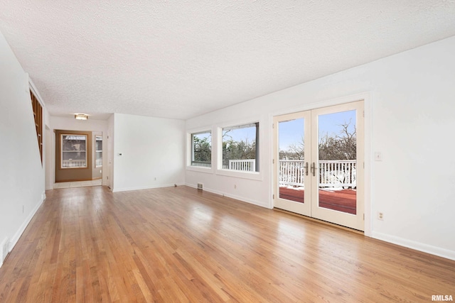 empty room featuring french doors, light hardwood / wood-style flooring, and a textured ceiling