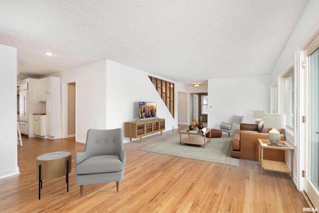 living room featuring a wealth of natural light, light hardwood / wood-style flooring, and a textured ceiling