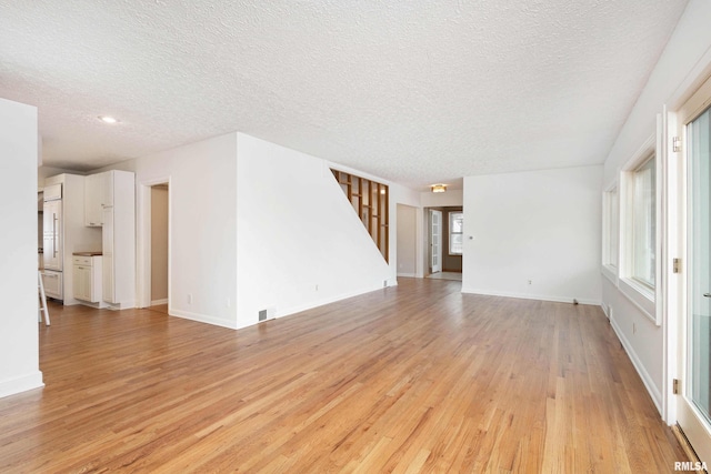 unfurnished living room featuring light hardwood / wood-style flooring and a textured ceiling