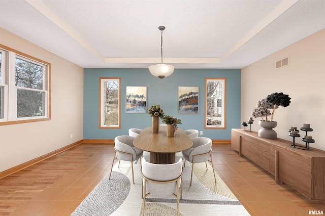 tiled dining space with a healthy amount of sunlight and a tray ceiling