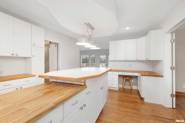 kitchen with wood counters, a barn door, hanging light fixtures, and white cabinets