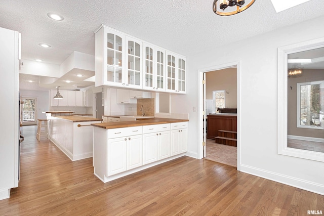 kitchen featuring white cabinets, wooden counters, and a textured ceiling