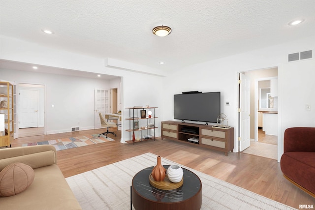 living room with a textured ceiling and light wood-type flooring