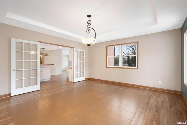 empty room with a tray ceiling and french doors