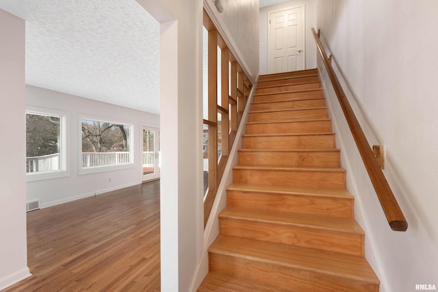 stairway featuring hardwood / wood-style flooring and a textured ceiling