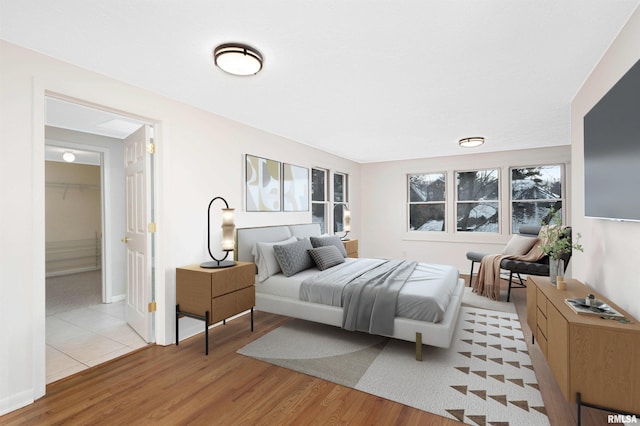 bedroom with a walk in closet and light wood-type flooring