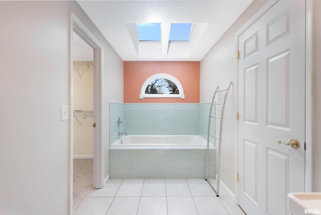 bathroom featuring a relaxing tiled tub, tile patterned flooring, and a skylight