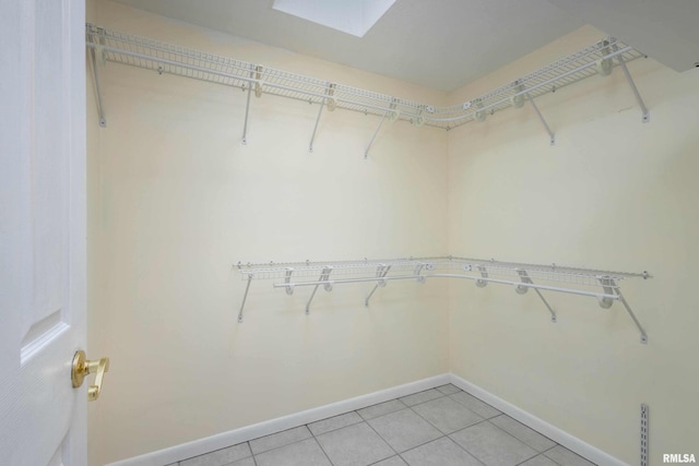 spacious closet with light tile patterned floors and a skylight