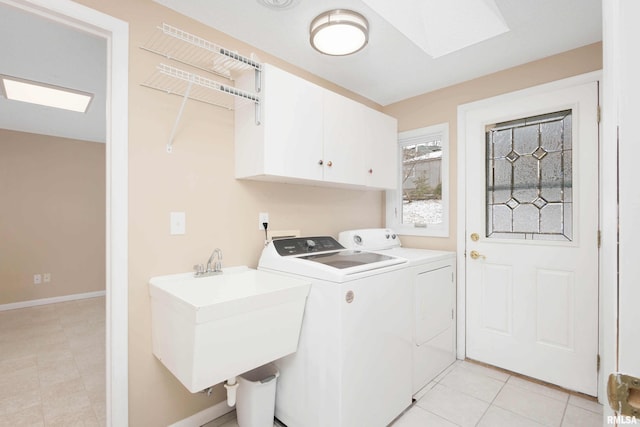 laundry area featuring sink, light tile patterned floors, a skylight, cabinets, and washing machine and clothes dryer