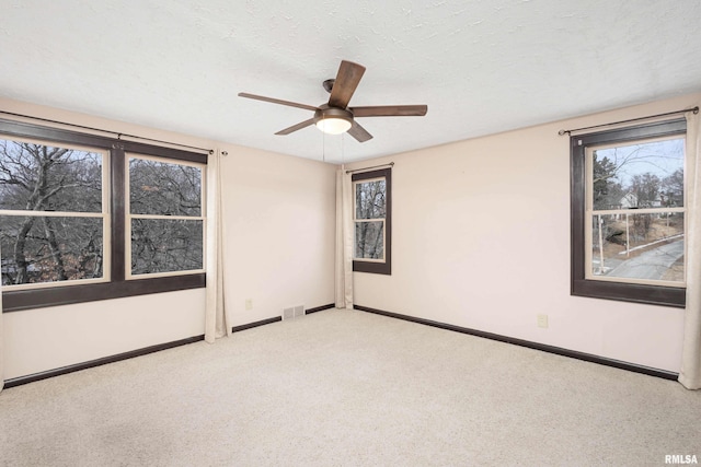 unfurnished room featuring ceiling fan, light colored carpet, and a textured ceiling