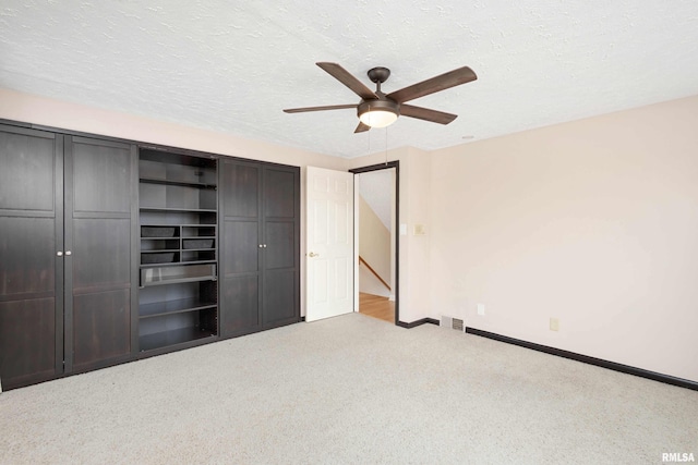 unfurnished bedroom with light carpet, a textured ceiling, ceiling fan, and a closet