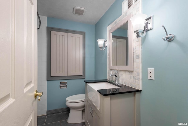 bathroom with tile patterned flooring, toilet, vanity, and decorative backsplash