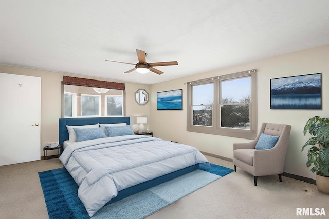 carpeted bedroom featuring multiple windows and ceiling fan