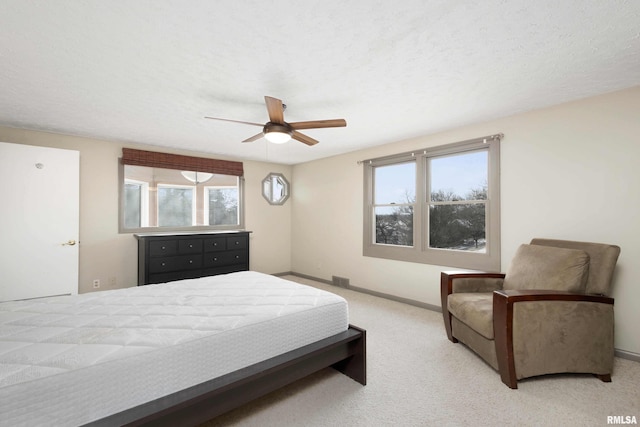 bedroom featuring ceiling fan, light colored carpet, and a textured ceiling