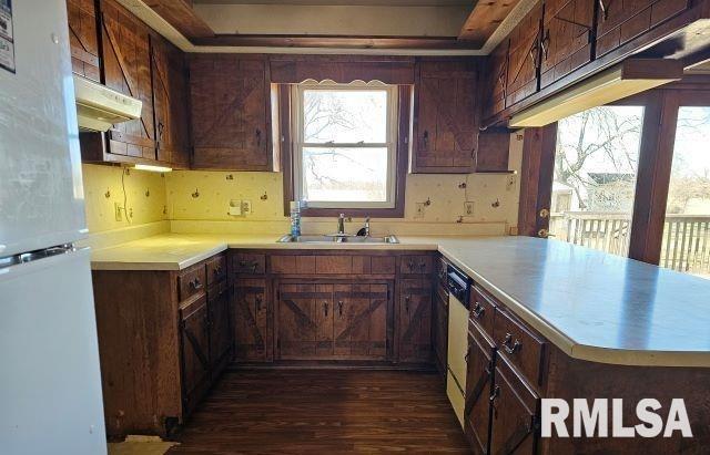 kitchen with dark brown cabinetry, sink, white refrigerator, kitchen peninsula, and dishwasher