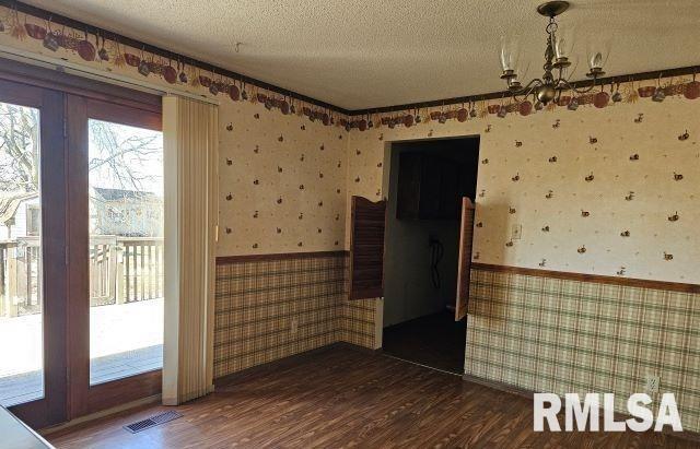 spare room with dark hardwood / wood-style flooring, a notable chandelier, and a textured ceiling