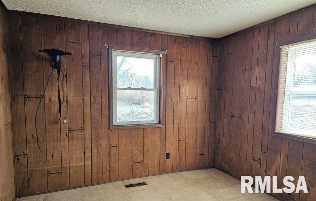 doorway to outside with a textured ceiling and wood walls