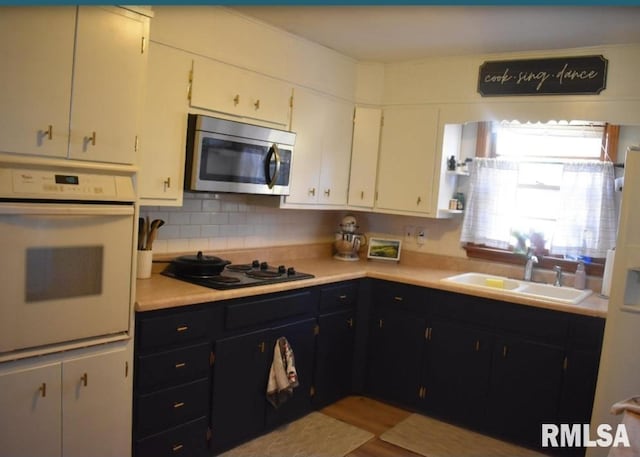 kitchen with black gas cooktop, sink, white oven, and white cabinets