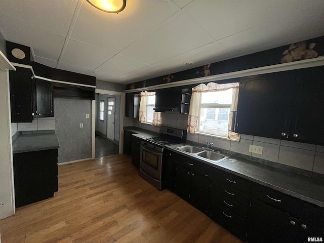 kitchen with wall chimney exhaust hood, sink, wood-type flooring, stainless steel range with gas cooktop, and decorative backsplash