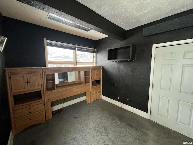 bedroom with dark colored carpet and a textured ceiling