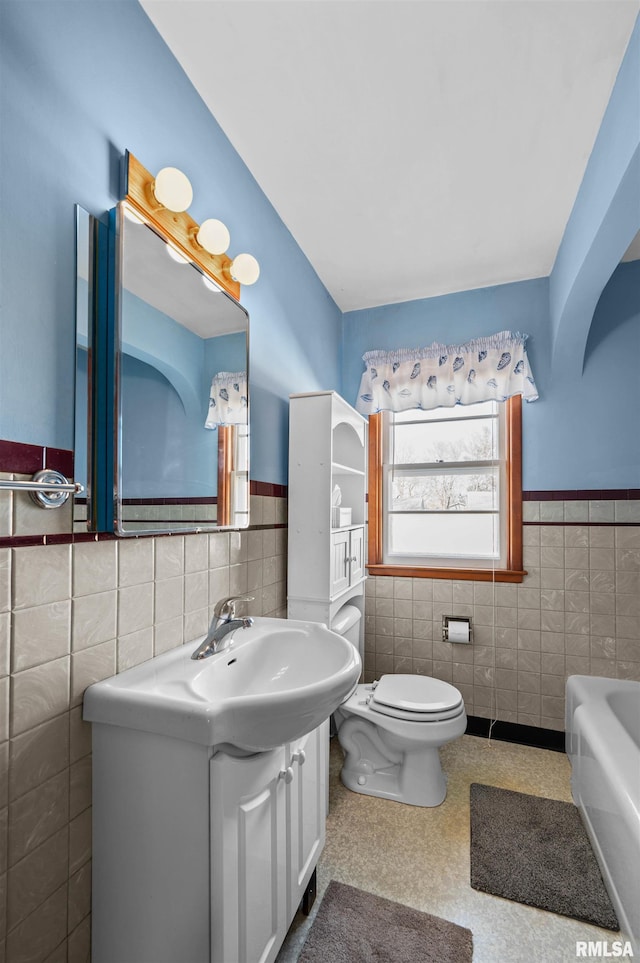 bathroom featuring vanity, tile walls, a bathtub, and toilet