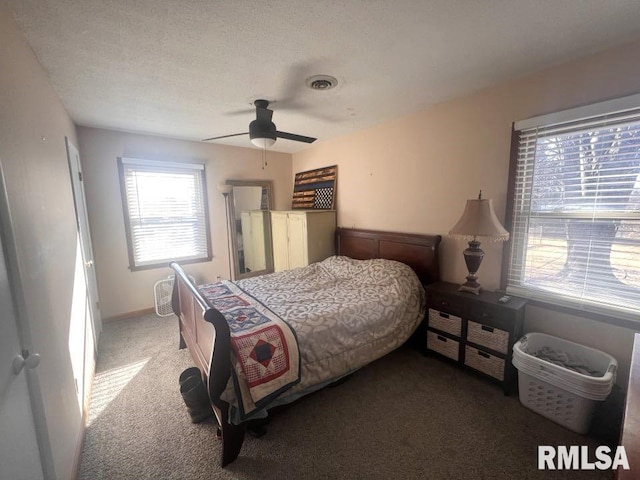 bedroom featuring dark colored carpet, a textured ceiling, and ceiling fan