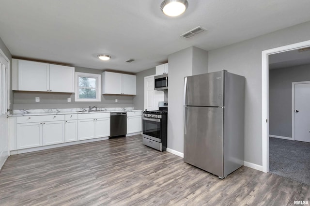 kitchen with white cabinetry, appliances with stainless steel finishes, wood-type flooring, and sink