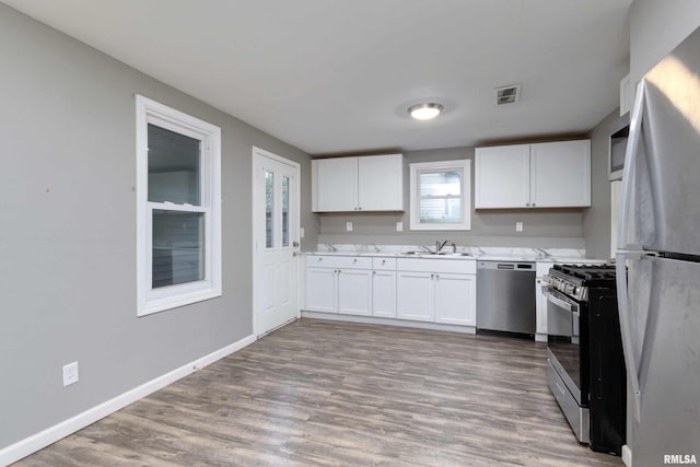 kitchen featuring white cabinetry, stainless steel appliances, sink, and light hardwood / wood-style flooring