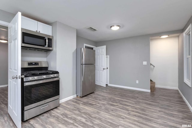 kitchen with white cabinetry, appliances with stainless steel finishes, and light hardwood / wood-style floors