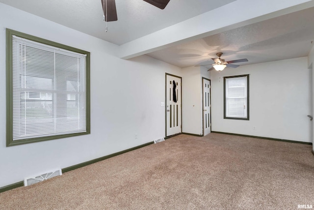 carpeted empty room with ceiling fan, beam ceiling, and a textured ceiling